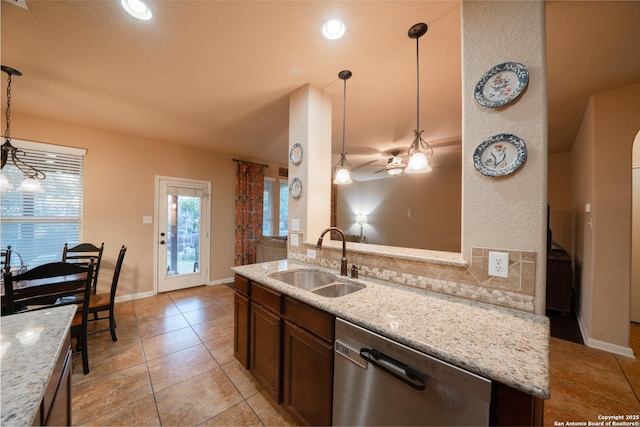 kitchen with a sink, light stone countertops, dishwasher, and decorative light fixtures