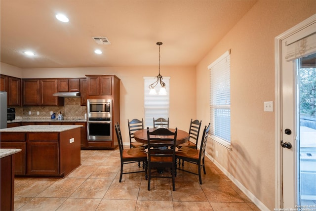 kitchen with light stone counters, pendant lighting, stainless steel appliances, visible vents, and decorative backsplash