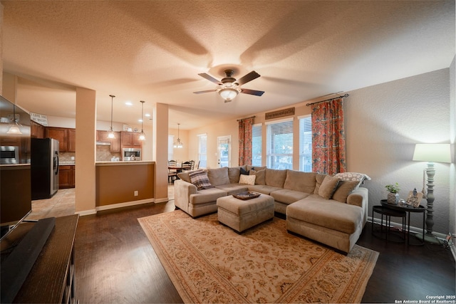 living room featuring ceiling fan, a textured ceiling, baseboards, and wood finished floors