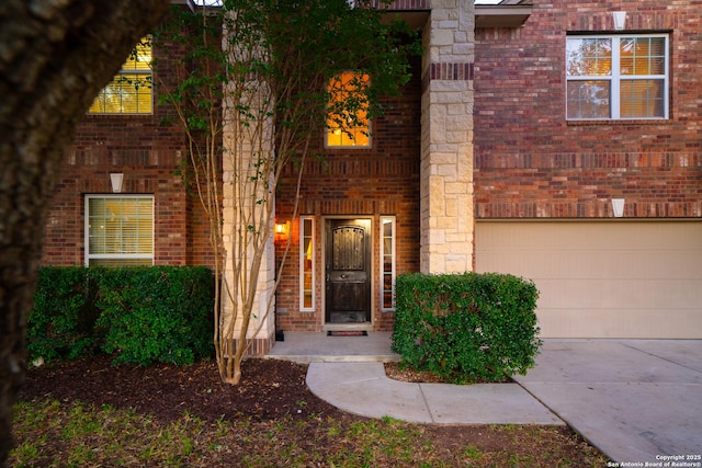 property entrance featuring a garage, brick siding, and driveway