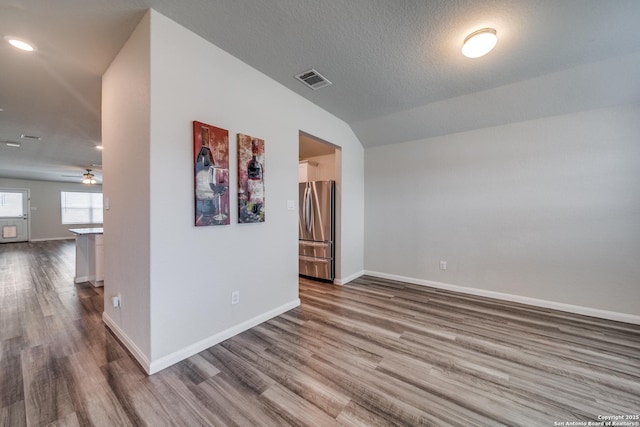 empty room featuring visible vents, a textured ceiling, baseboards, and wood finished floors