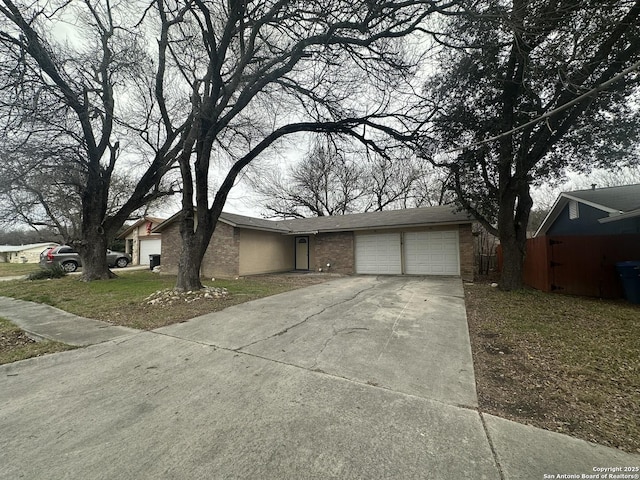 view of front of house featuring an attached garage, a front lawn, concrete driveway, and brick siding