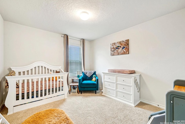 carpeted bedroom with a nursery area and a textured ceiling