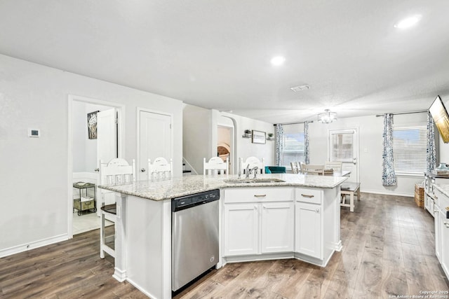 kitchen with white cabinets, dishwasher, light stone countertops, a kitchen island with sink, and a sink