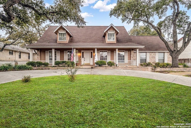 new england style home with a porch, roof with shingles, and a front lawn