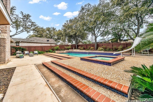 view of swimming pool featuring a water slide, a fenced backyard, an in ground hot tub, a fenced in pool, and a patio area