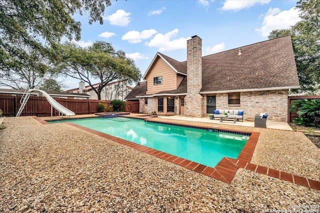 view of pool with a pool with connected hot tub, a patio area, a water slide, a fenced backyard, and an outdoor living space