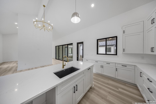 31047 Windmill Ln, Bulverde, TX 78163 - kitchen featuring a sink, white cabinetry, high vaulted ceiling, a chandelier, and light wood-style floors