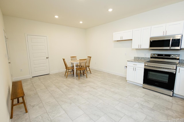 kitchen featuring baseboards, white cabinets, light stone countertops, stainless steel appliances, and recessed lighting