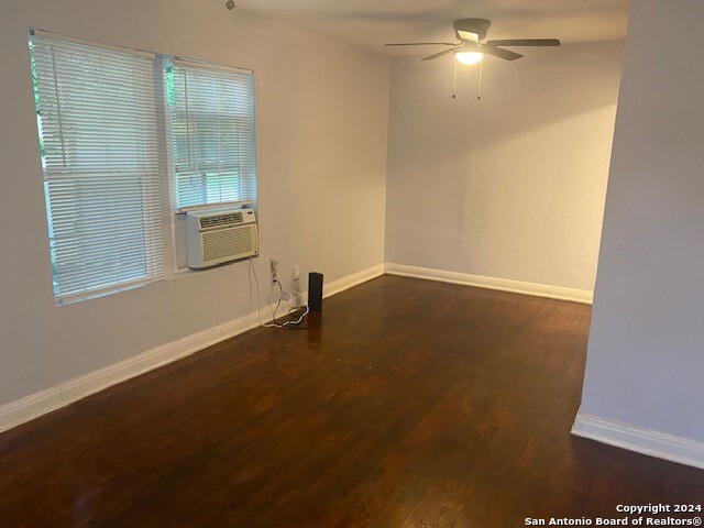 spare room featuring dark wood-style floors, cooling unit, ceiling fan, and baseboards