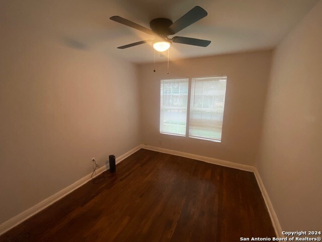 unfurnished room with dark wood-type flooring, ceiling fan, and baseboards
