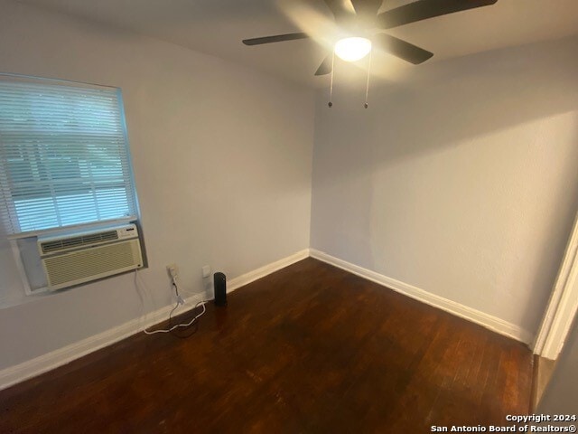 unfurnished room with dark wood-type flooring, cooling unit, a ceiling fan, and baseboards