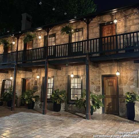 back of house at twilight with stone siding and a patio area