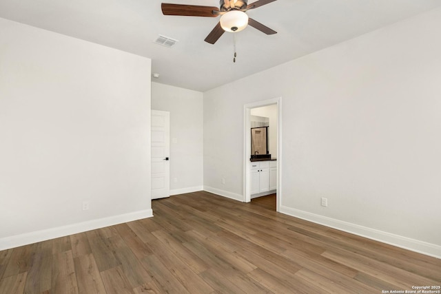 spare room featuring a ceiling fan, baseboards, visible vents, and dark wood-style flooring