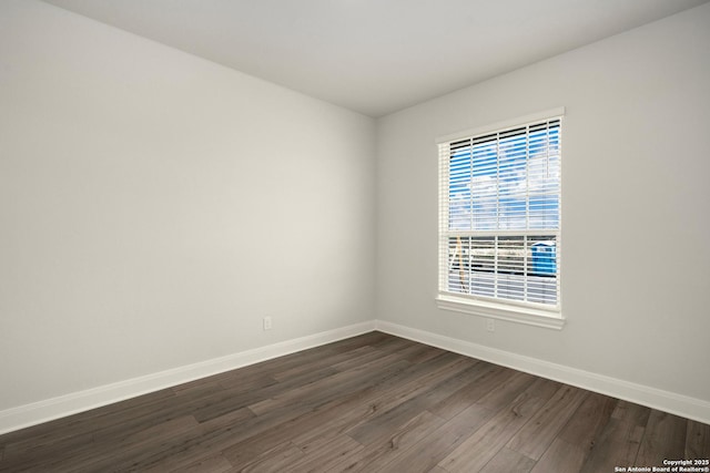 spare room featuring dark wood-style flooring and baseboards