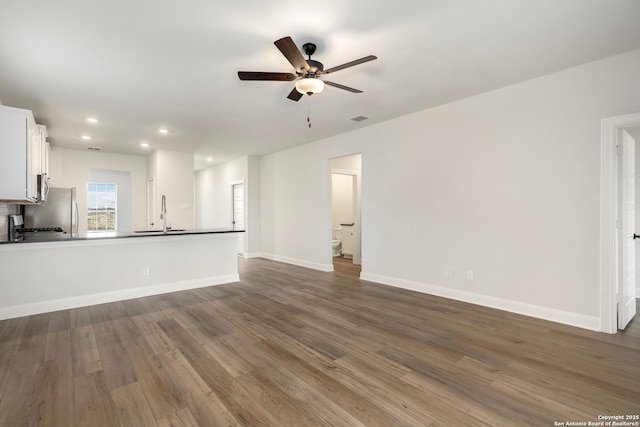 unfurnished living room featuring baseboards, visible vents, a ceiling fan, dark wood-type flooring, and recessed lighting