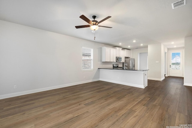 kitchen with stainless steel appliances, dark countertops, visible vents, white cabinetry, and a peninsula