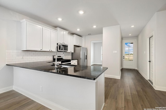 kitchen featuring a peninsula, appliances with stainless steel finishes, dark wood finished floors, and white cabinetry