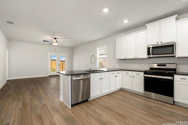 kitchen with dark countertops, white cabinetry, stainless steel appliances, and a sink