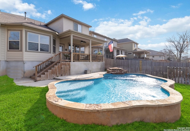 view of pool featuring a fire pit, a ceiling fan, stairway, fence, and a yard