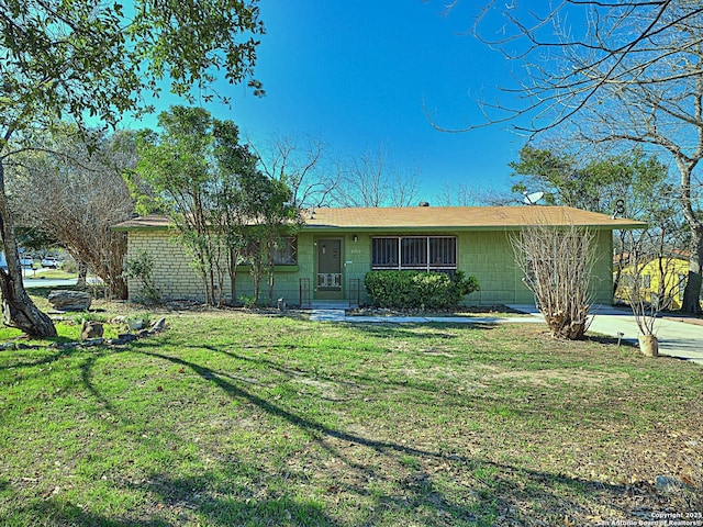 ranch-style home featuring concrete block siding and a front yard