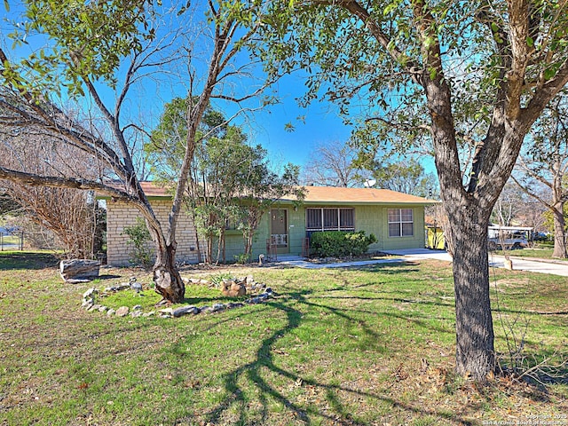 single story home featuring concrete block siding and a front lawn