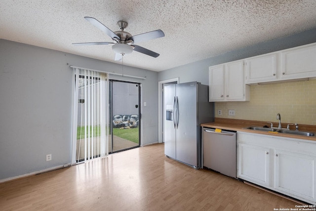 kitchen featuring stainless steel appliances, light wood-type flooring, white cabinets, and a sink