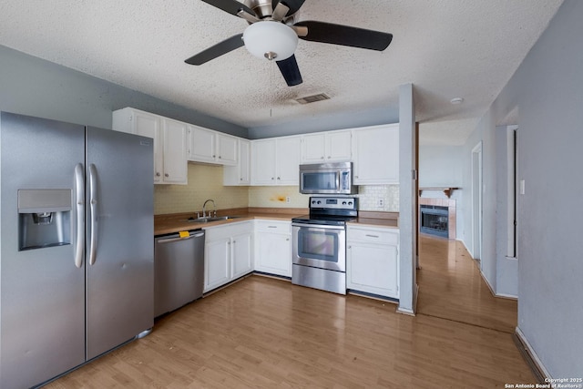 kitchen with visible vents, stainless steel appliances, a sink, and white cabinetry