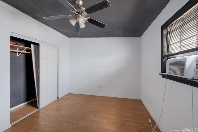 unfurnished bedroom featuring ceiling fan, a closet, cooling unit, and wood finished floors