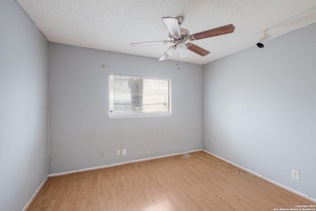 empty room with a textured ceiling, ceiling fan, baseboards, and light wood-style floors