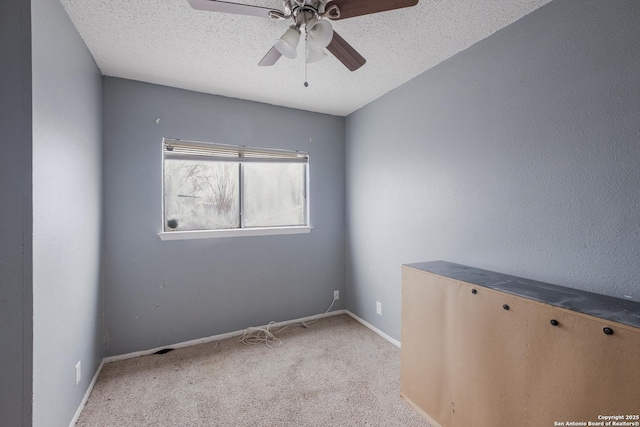 spare room with light carpet, a textured ceiling, a ceiling fan, and baseboards