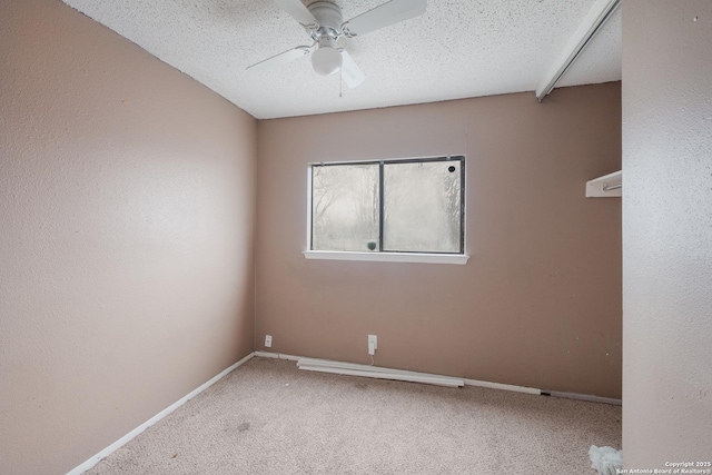 spare room with a textured ceiling, carpet, a ceiling fan, and baseboards