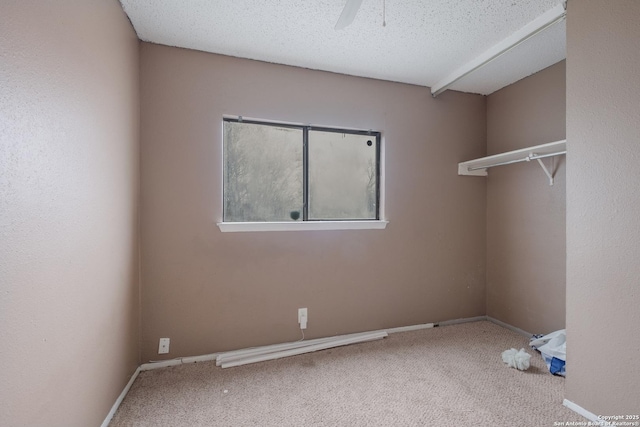 carpeted spare room with a textured ceiling, a ceiling fan, and baseboards