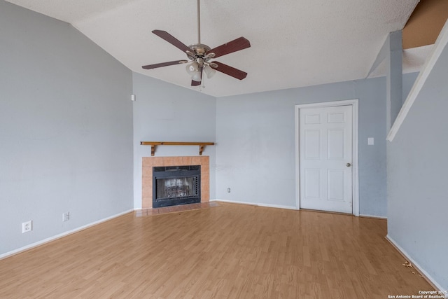 unfurnished living room featuring baseboards, lofted ceiling, light wood-style flooring, ceiling fan, and a fireplace