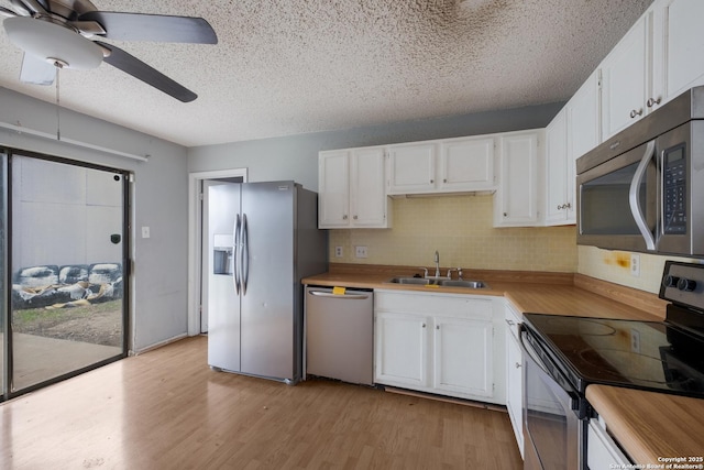 kitchen with a sink, white cabinets, stainless steel appliances, and light countertops