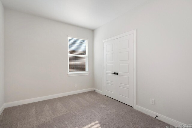 spare room featuring baseboards and light colored carpet