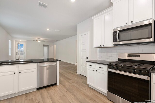 kitchen with visible vents, white cabinets, appliances with stainless steel finishes, a sink, and backsplash