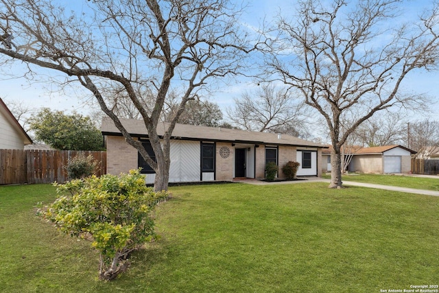 view of front of house with brick siding, a front yard, and fence