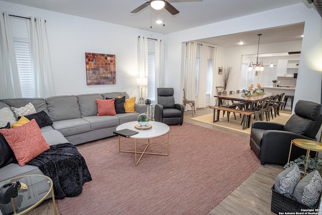 living area featuring recessed lighting, light wood-style flooring, and ceiling fan with notable chandelier