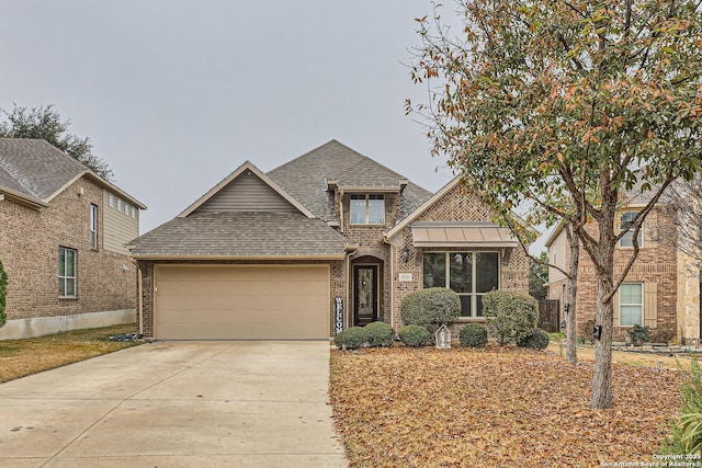 view of front of house with driveway, roof with shingles, an attached garage, a standing seam roof, and brick siding