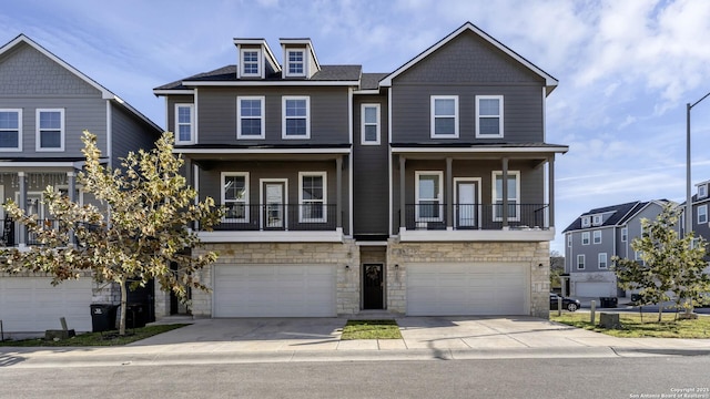 view of property featuring driveway, stone siding, and a garage