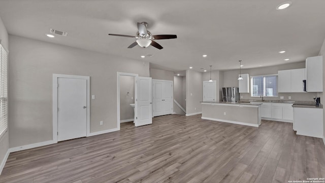 kitchen with a kitchen island, visible vents, white cabinets, hanging light fixtures, and freestanding refrigerator