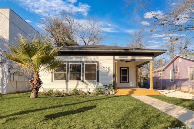 bungalow featuring covered porch, ceiling fan, fence, and a front lawn