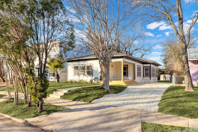 view of front of house featuring driveway, fence, and a front lawn