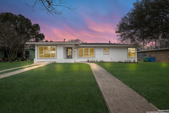 view of front of home featuring stucco siding and a yard