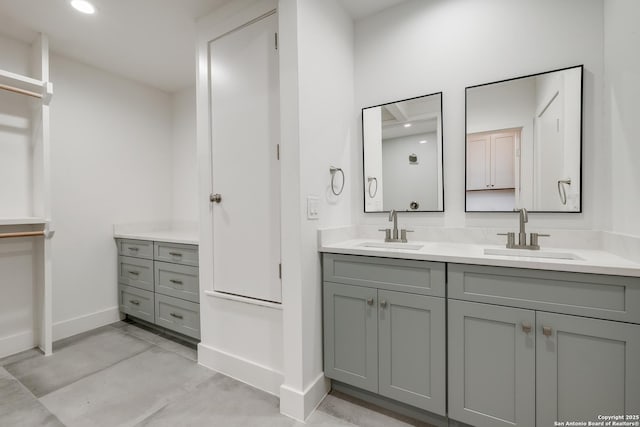 bathroom with recessed lighting, a sink, baseboards, and double vanity