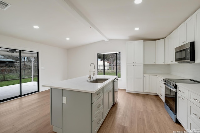 kitchen with stainless steel appliances, white cabinets, light countertops, and a sink