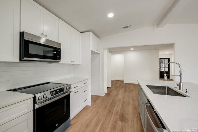 kitchen with visible vents, white cabinetry, stainless steel appliances, and a sink