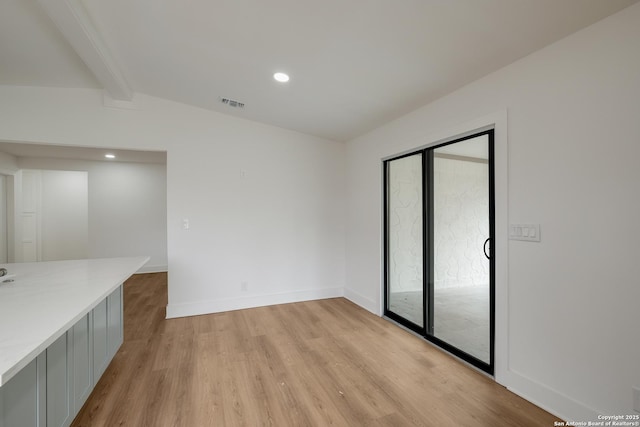 spare room featuring vaulted ceiling with beams, light wood finished floors, recessed lighting, visible vents, and baseboards