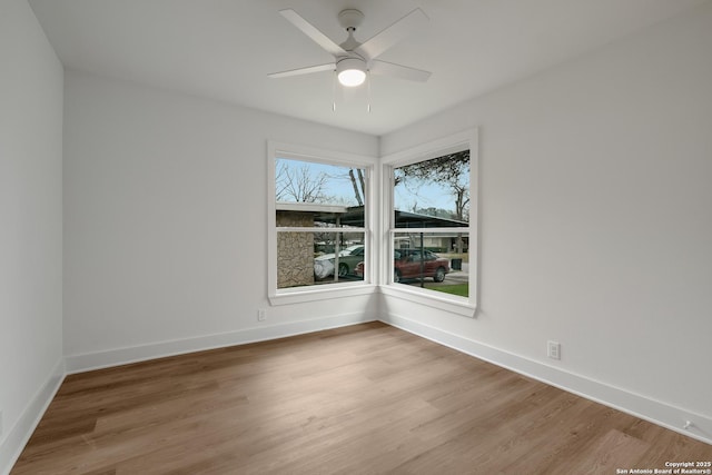 unfurnished room featuring a ceiling fan, light wood-style flooring, and baseboards